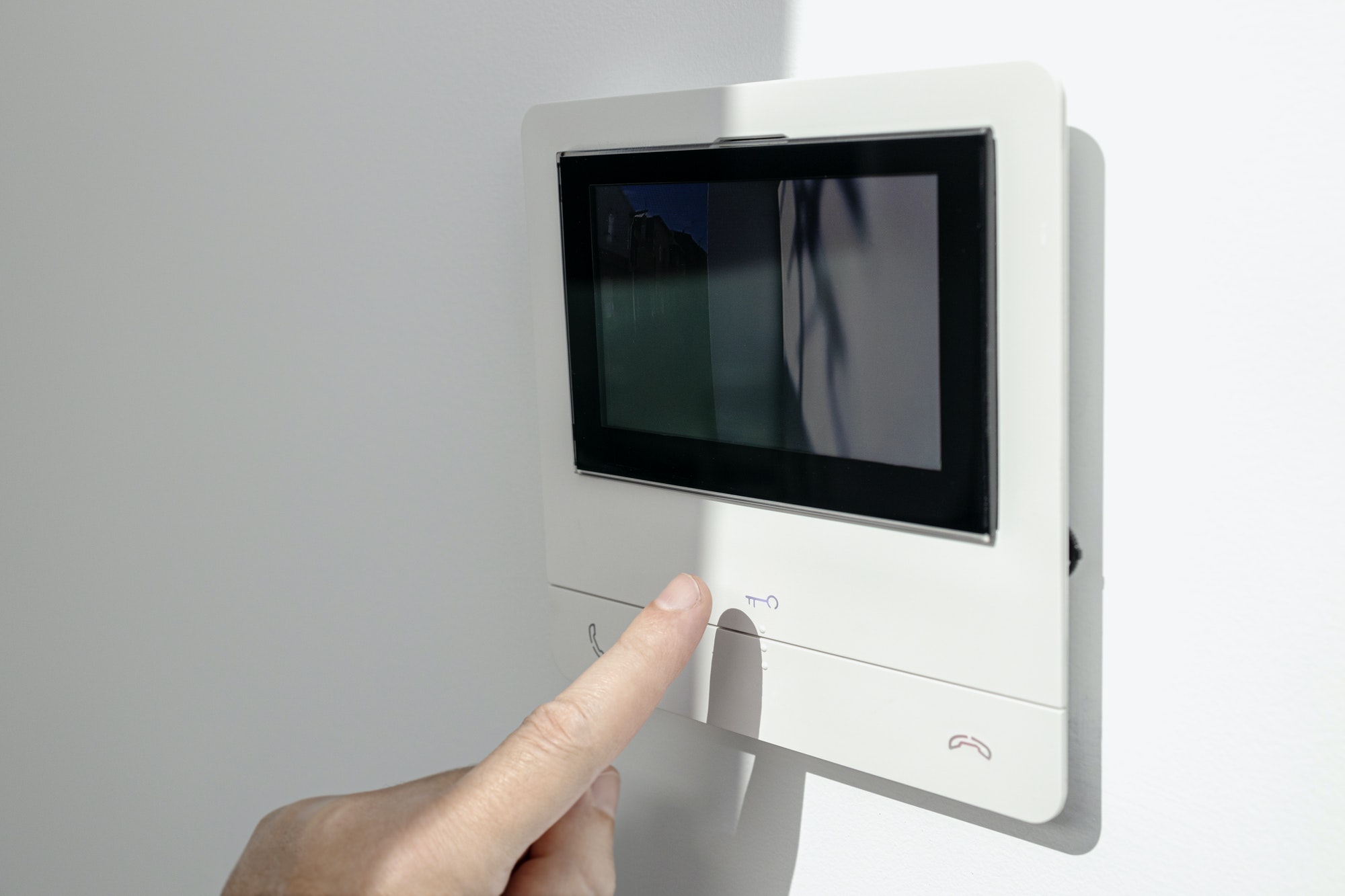 Intercom in home interior and a hand ready to open the door button
